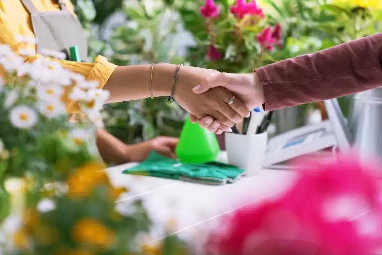Florist and customer shaking hands at the plant shop, hands close up