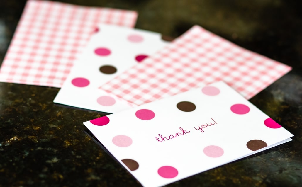 thank you cards in pink and purple scattered on a table