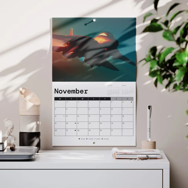 Stapled wall calendar hanging open with a photograph above the monthly date grid and a drilled hanging hole