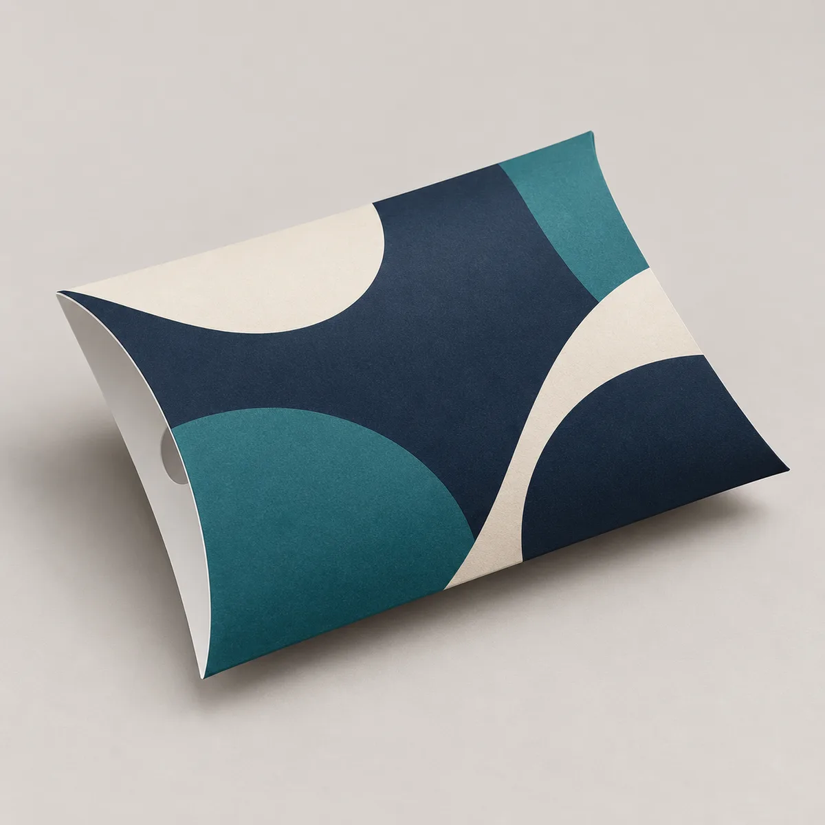 Illustrative printed pillow box with navy and teal geometric artwork