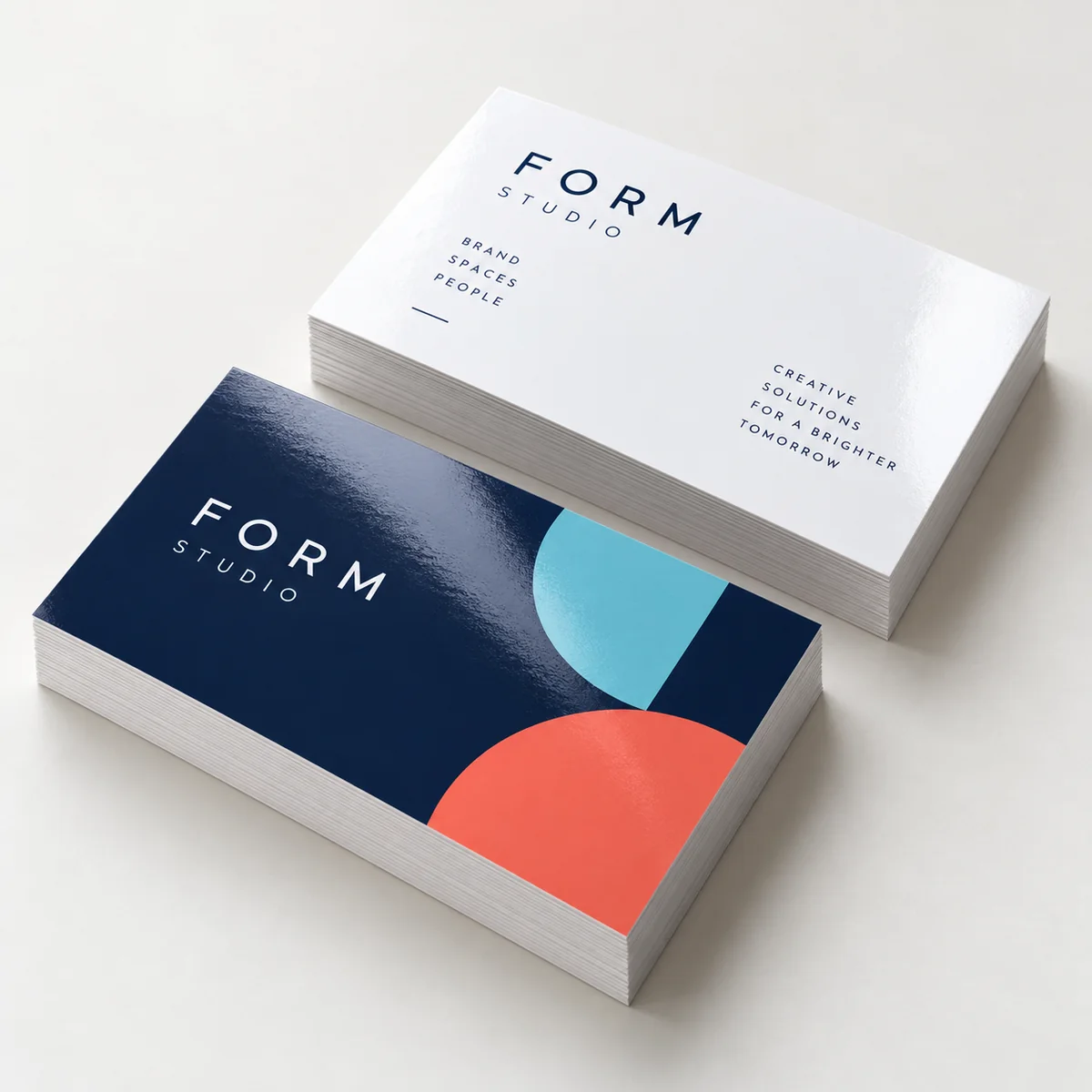 Illustration of two stacks of gloss-laminated rectangular business cards with navy, cyan, coral and white artwork