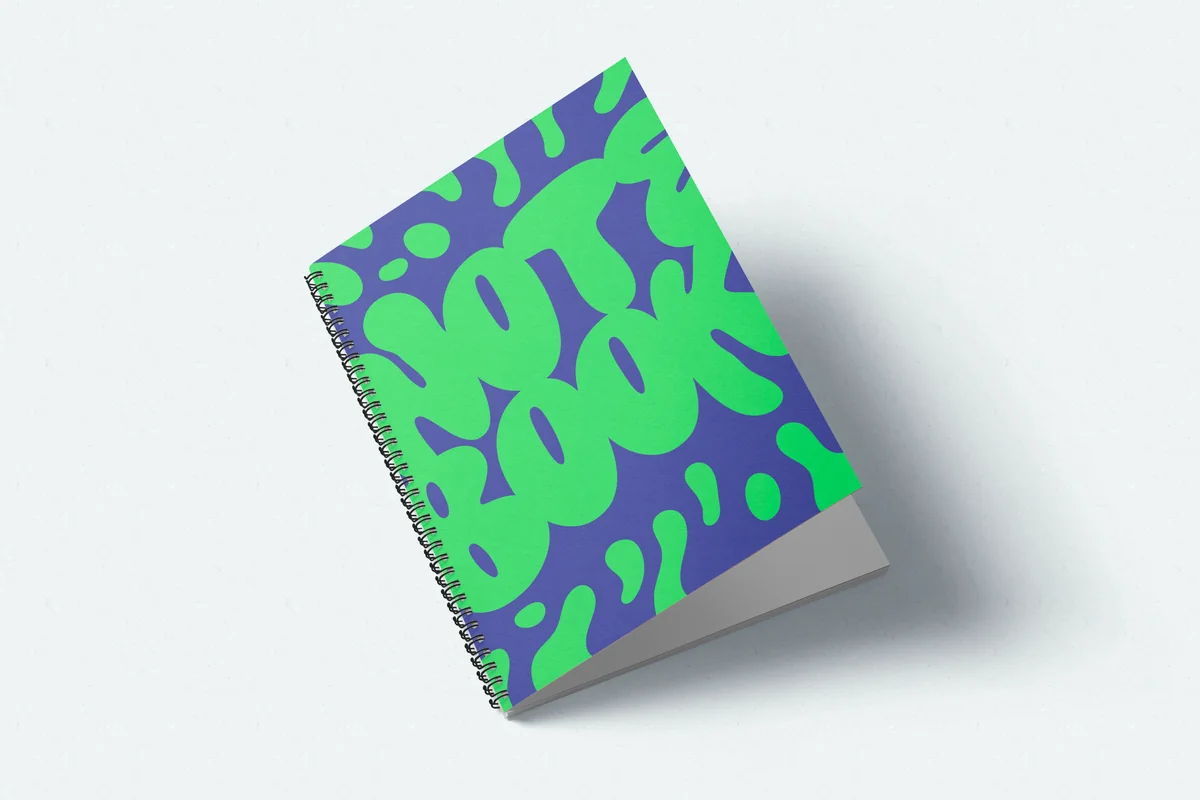 Closed silver wire-bound notebook with a green and blue abstract printed cover